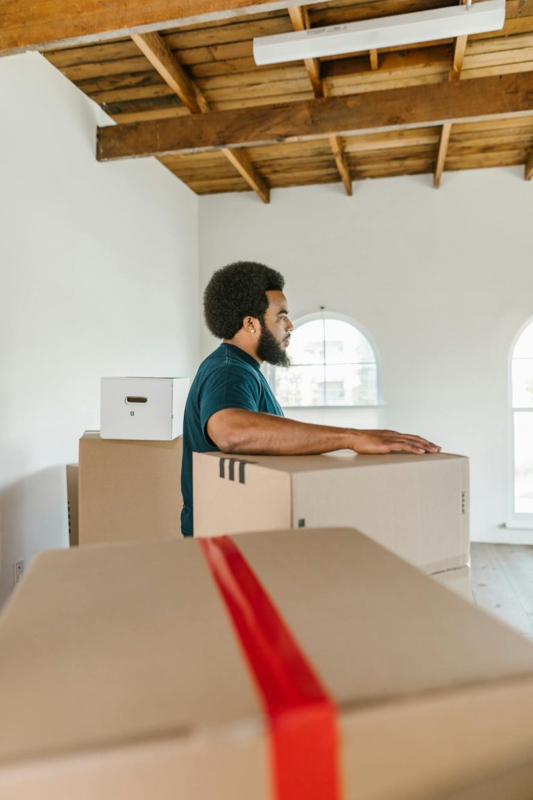 Man handling moving boxes in a spacious, modern room during relocation.